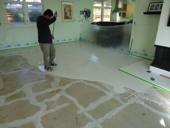 Technician spreading polymer overlay coating across a residential concrete floor in a North Bay California home