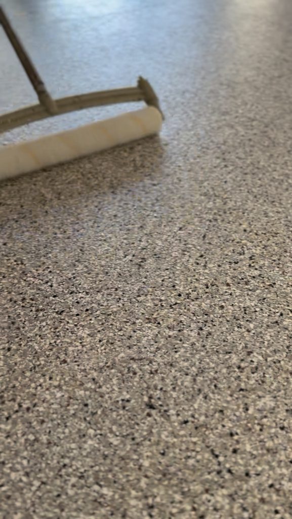 Squeegee spreading vinyl chip epoxy flake coating across a garage floor in North Bay California