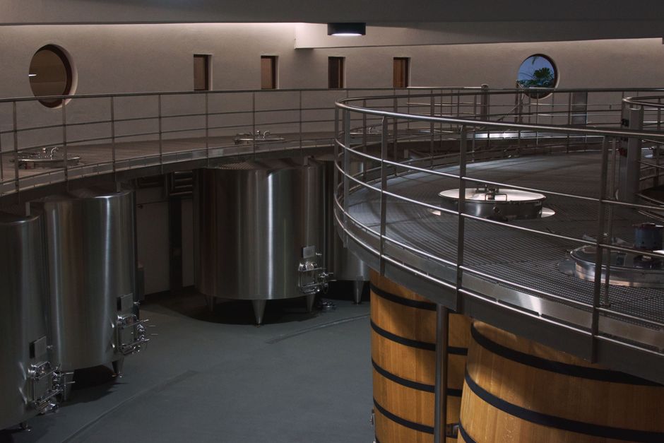 Modern winery interior with stainless steel vats and barrels over a smooth concrete floor — winery concrete floor finishing